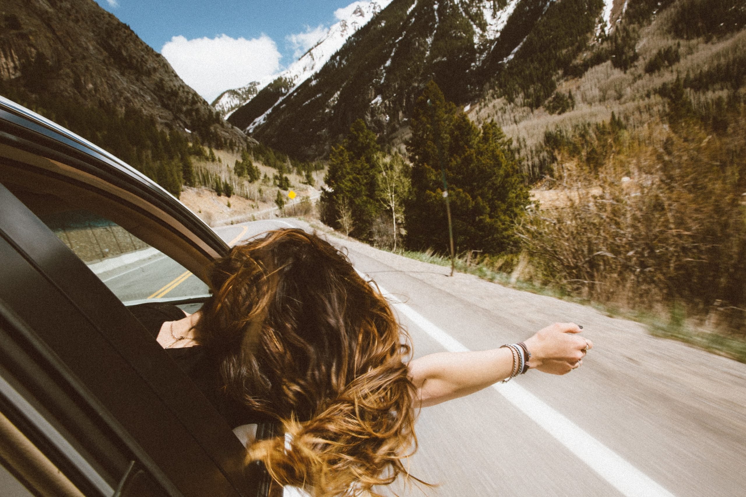 girl leaning out a window while on a road trip
